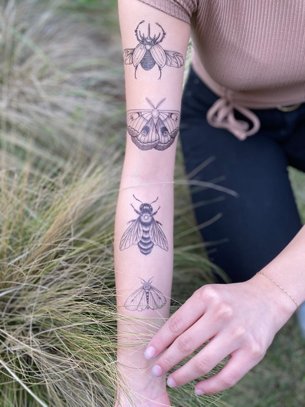 temporary tattoos on persons arm wearing brown and black in a nature background 
