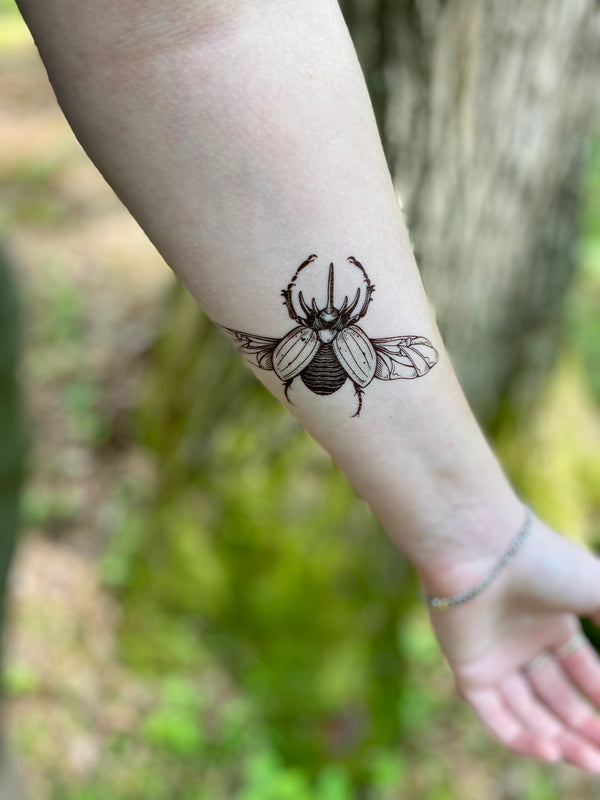 Rhinoceros beetle temporary tattoo on persons arm in a nature blurred background 