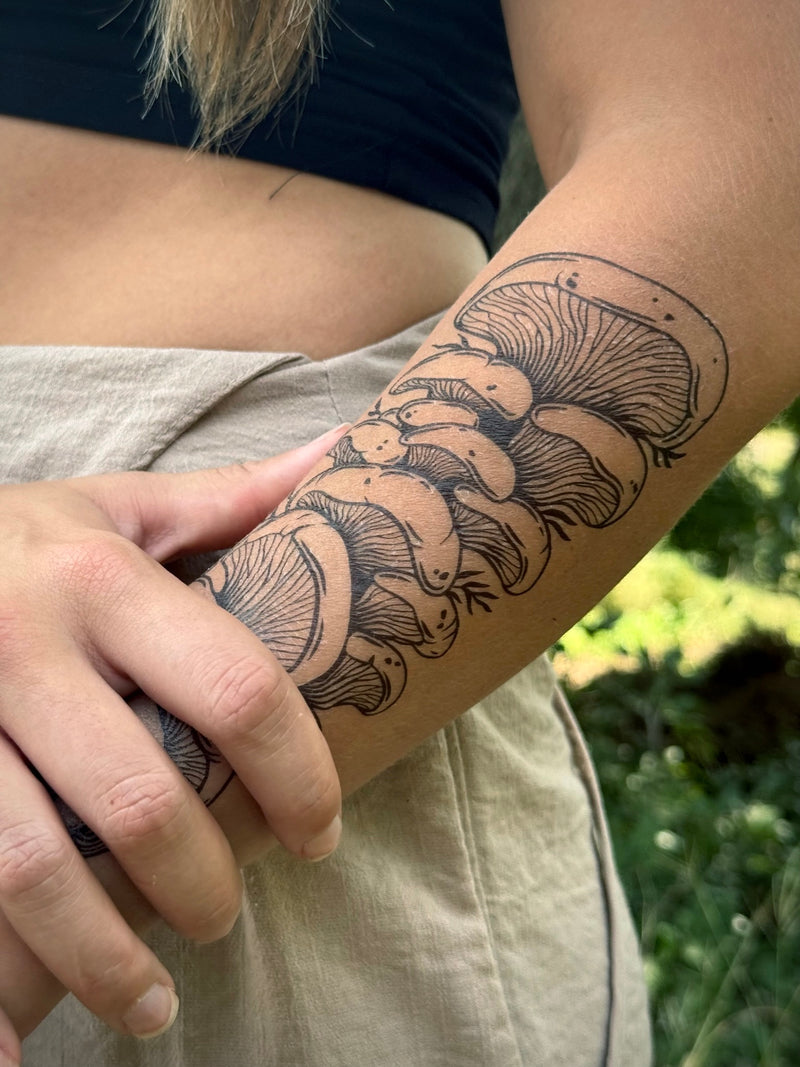 Person with a detailed arm  temporary tattoo of mushrooms outdoors