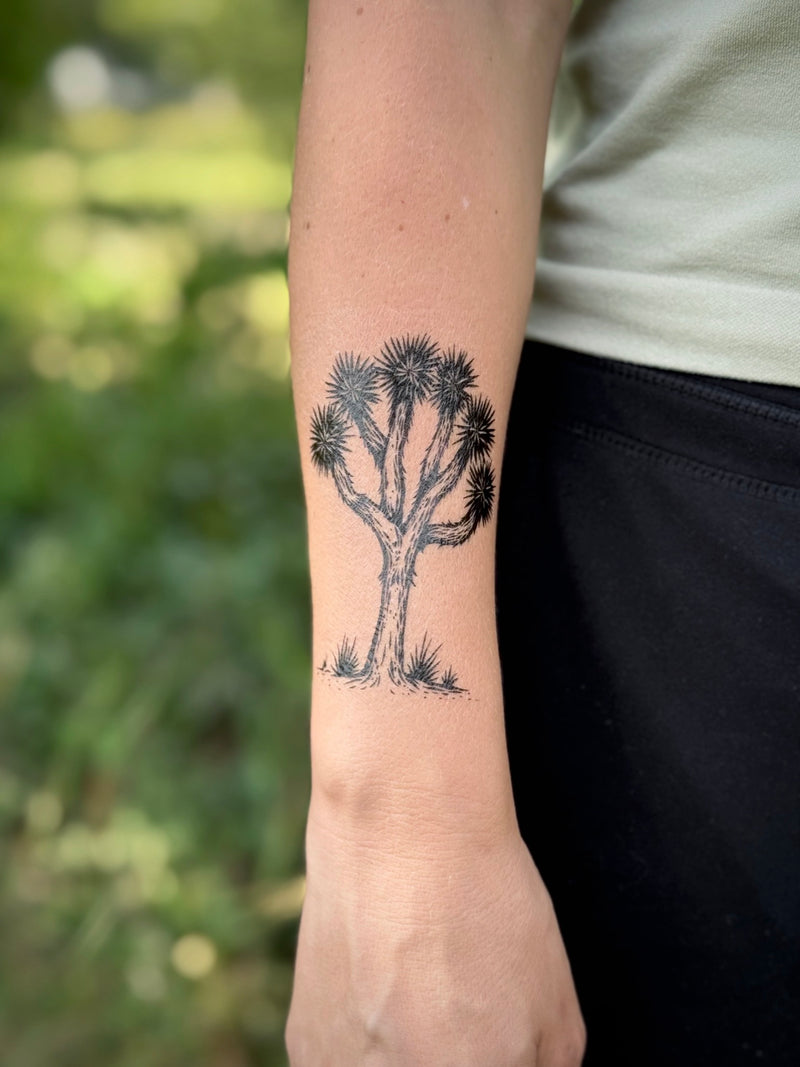  Temporary Tattoo of a joshua tree design on a person's arm with a blurred natural background