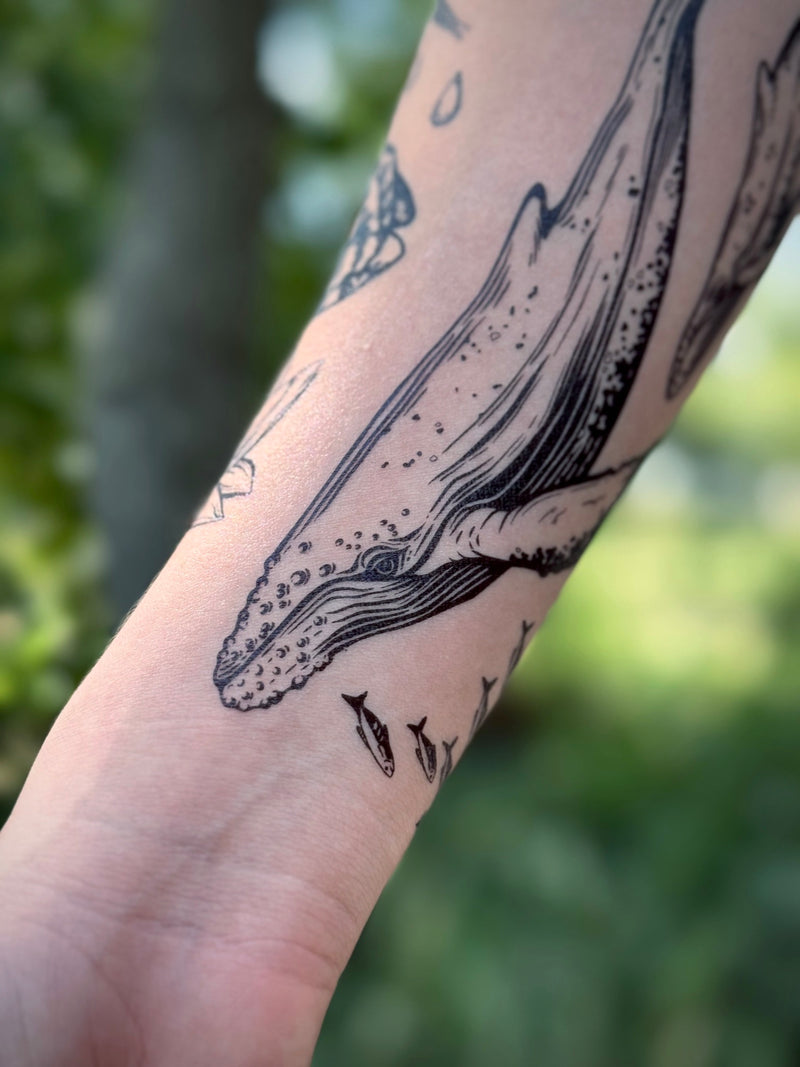 temporary Tattoo of a whale on a person's arm with a blurred green background
