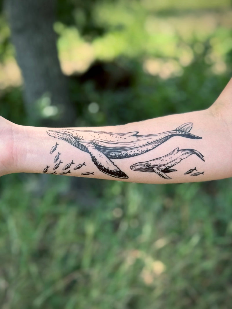 temporary Tattoo of a whale and fish on a person's arm with a natural background