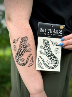 Person with a salamander temporary tattoo on their arm holding a package of Nature Tats temporary tattoos.