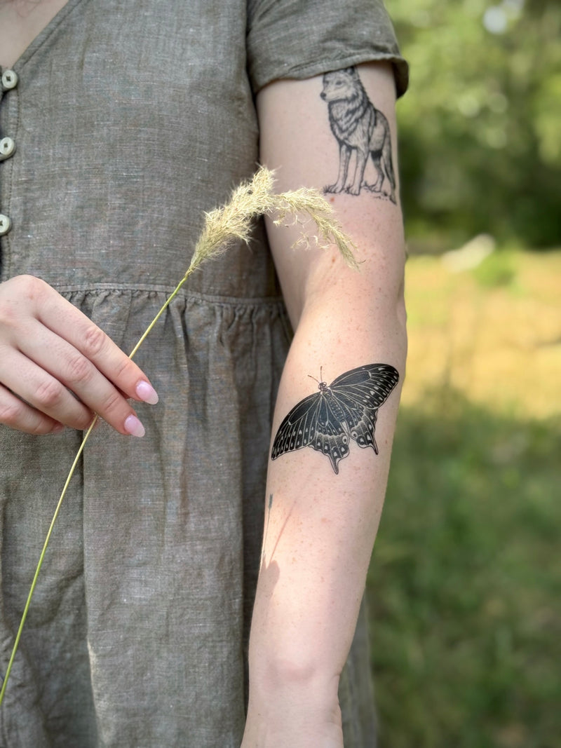 Person wearing a temporary tattoos outdoors with greenery in the background