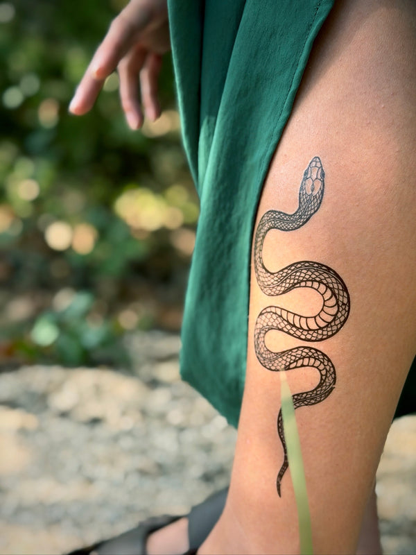 Person with a snake temporary tattoo on their leg outdoors
