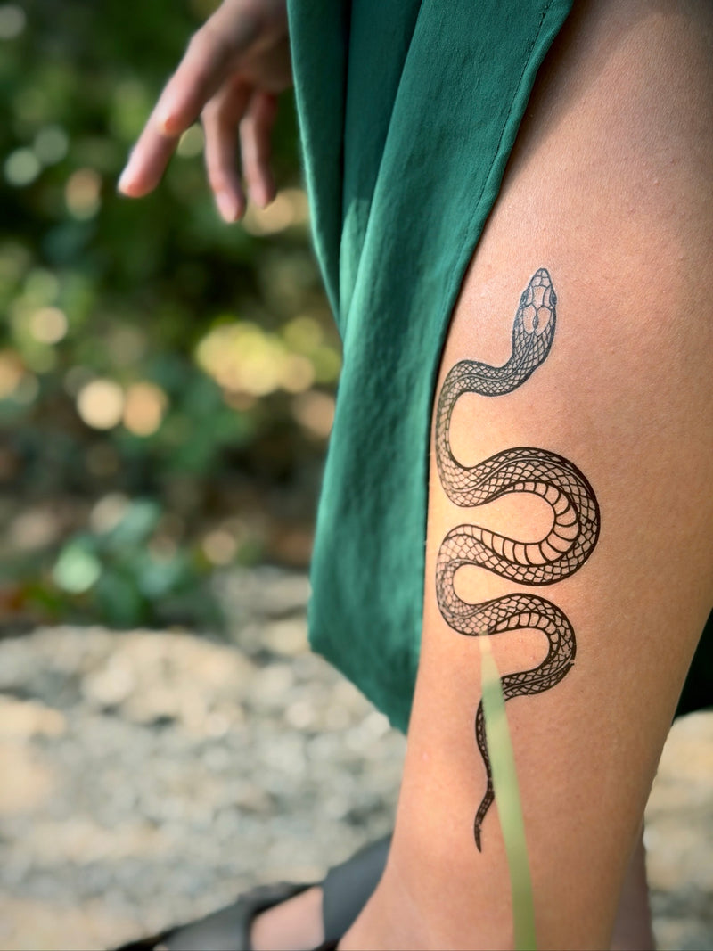 Person with a snake temporary tattoo on their leg outdoors
