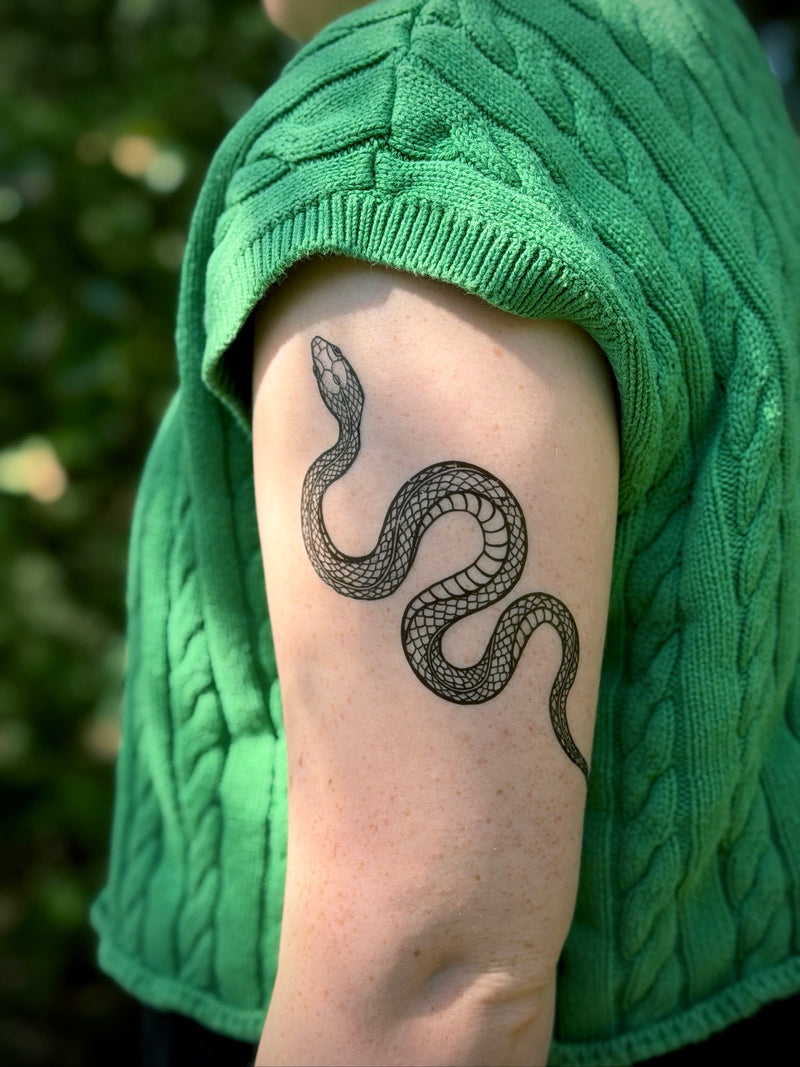 Person wearing a green sweater with a snake temporary tattoo on their arm 