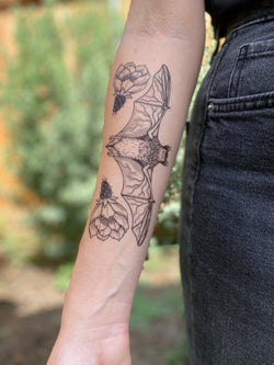 free-tailed bat temporary tattoo on person arm wearing black in a blurred nature background 