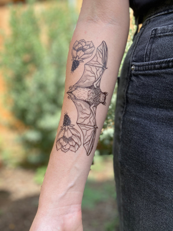 free-tailed bat temporary tattoo on person arm wearing black in a blurred nature background 