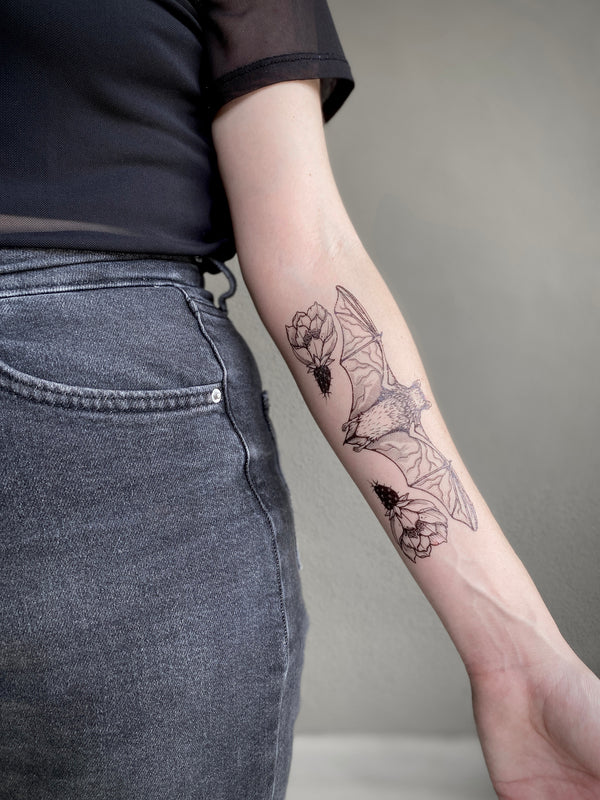 free-tailed bat temporary tattoo on persons arm wearing black with a grey background 