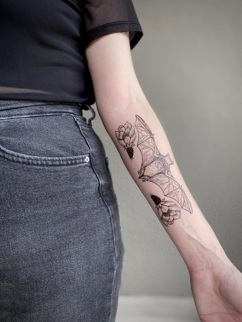 free-tailed bat temporary tattoo on persons arm wearing black with a grey background 