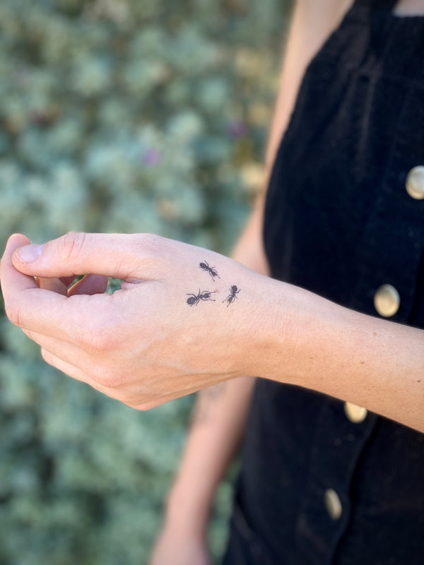 temporary tattoos of small ants on hand with a blurred green nature background 
