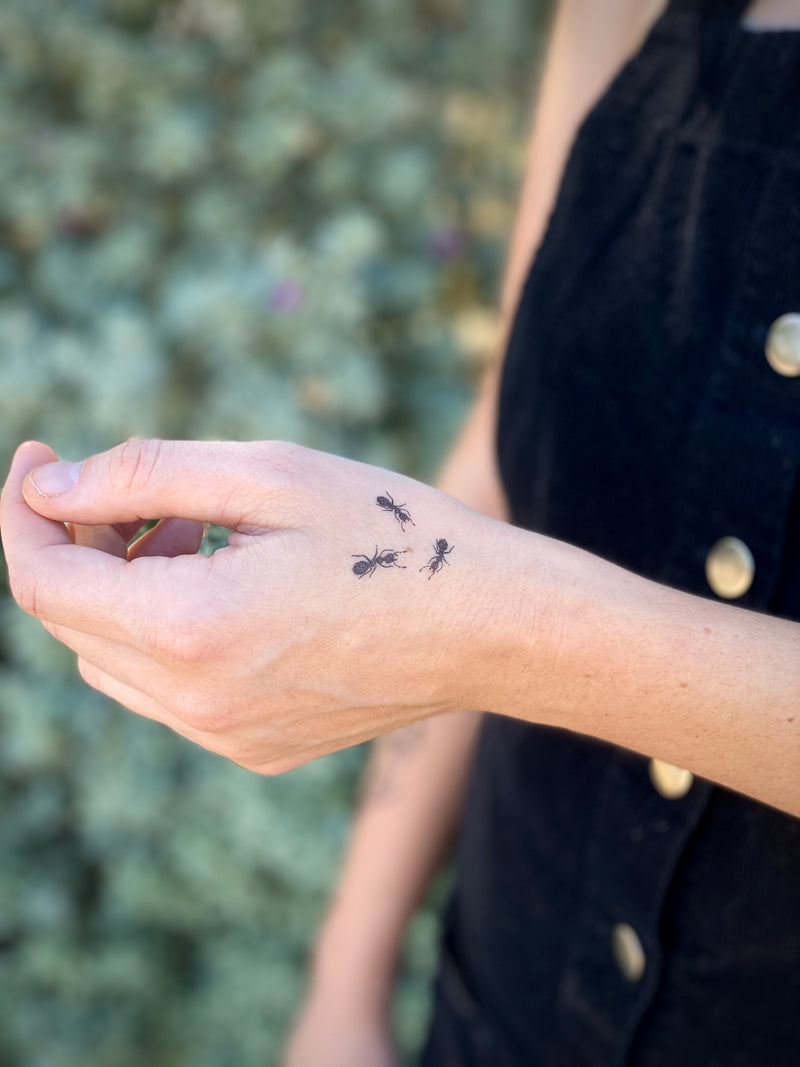 temporary tattoos of small ants on hand with a blurred green nature background 