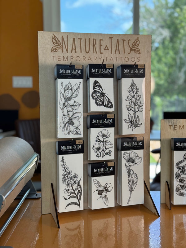 Nature-Tats temporary tattoos displayed on a stand with a blurred indoor background