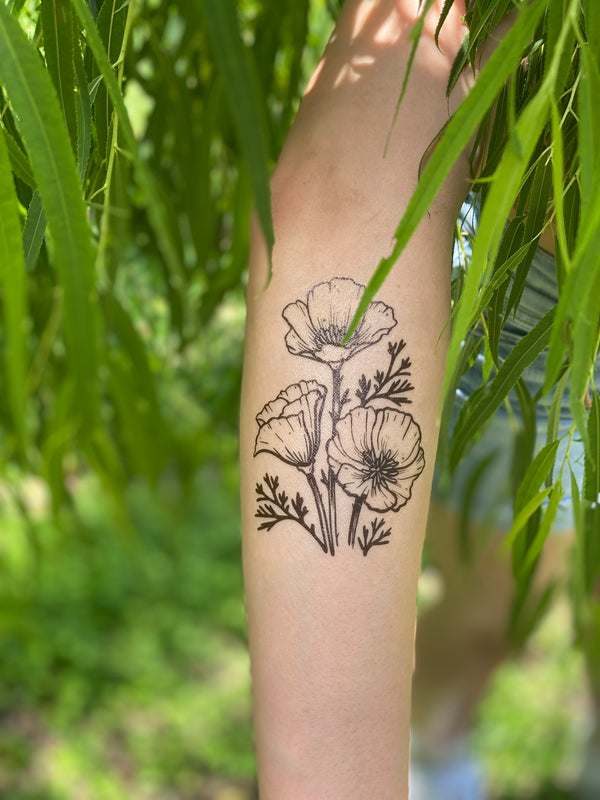 golden poppy on persons arm in a leafy green nature background 