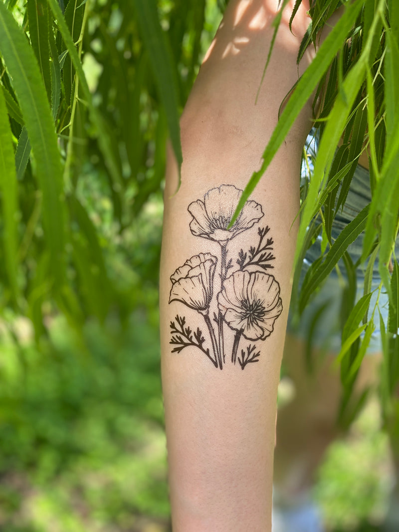golden poppy on persons arm in a leafy green nature background 