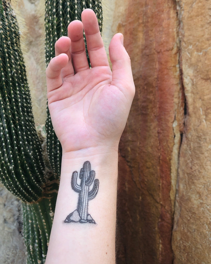 cactus temporary tattoo on wrist with a rock and cactus nature background 
