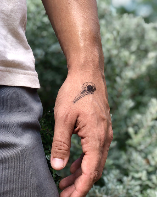 small bird skull on hand temporary tattoo with blurred nature background 