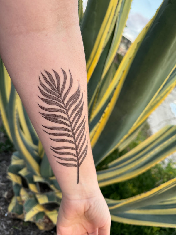 palm leaf temporary tattoo on persons arm in a green nature background 