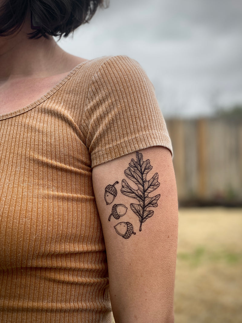 Person wearing a tan shirt with a nature-themed temporary tattoo on their arm.