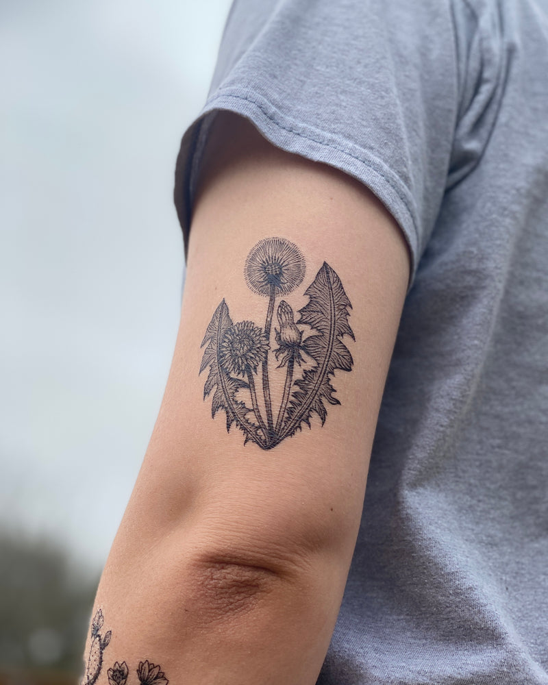 Dandelion temporary tattoo on back of arm with a blurred nature background 
