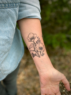 Temporary Tattoo of golden poppy flower design on a person's arm with a natural background