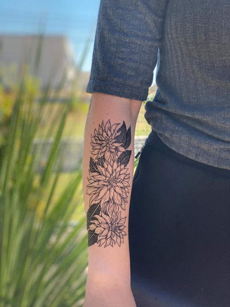 person wearing black ink dahlia temporary tattoo on forearm