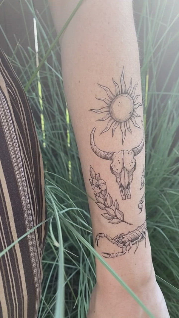 sunlit south temporary tattoo collection on persons arm wearing brown in a green nature background 