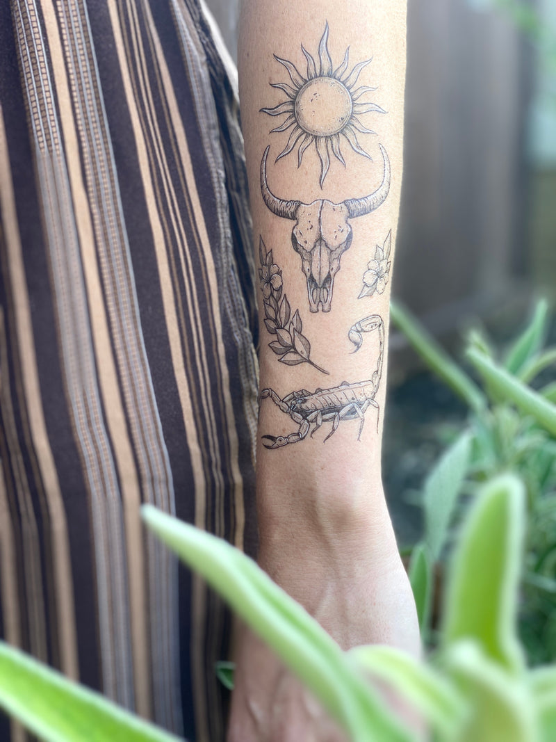 sunlit south temporary tattoo collection on persons arm wearing brown in blurred nature background 