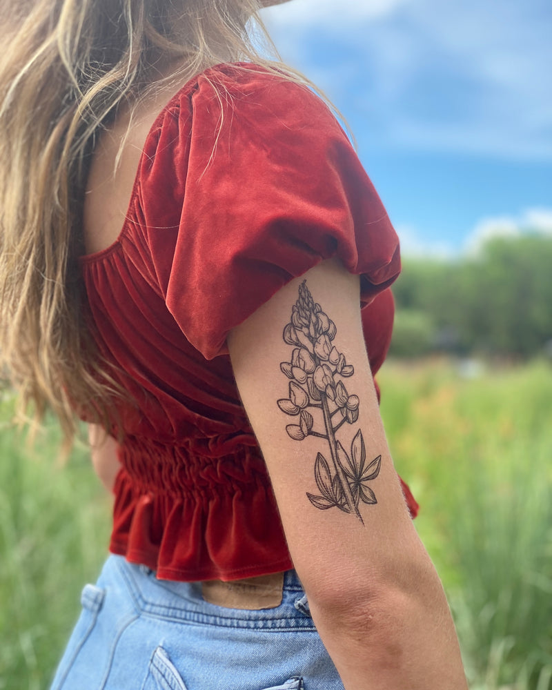 bluebonnet temporary tattoo on a persons arm with blurred nature background