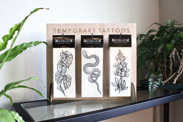 Sets of temporary tattoos on stand with plants around it 