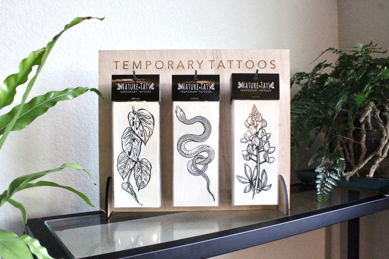Sets of temporary tattoos on stand with plants around it 