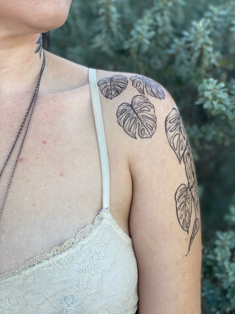 monstera vine on persons shoulder wearing white in a green blurred nature background 