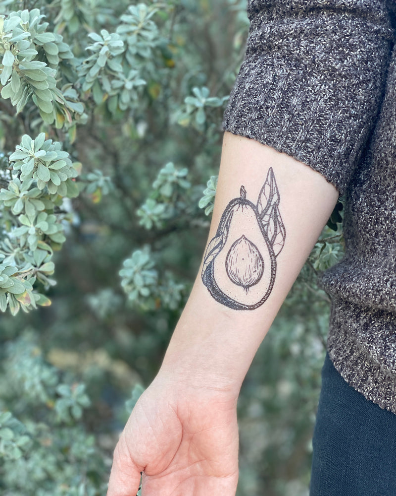 avocado temporary tattoo on a person arm with a green nature background 