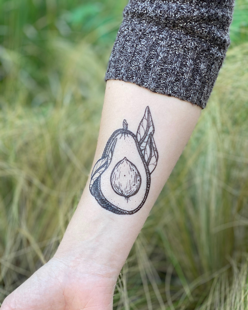 avocado temporary tattoo on a person wrist in a green nature background 