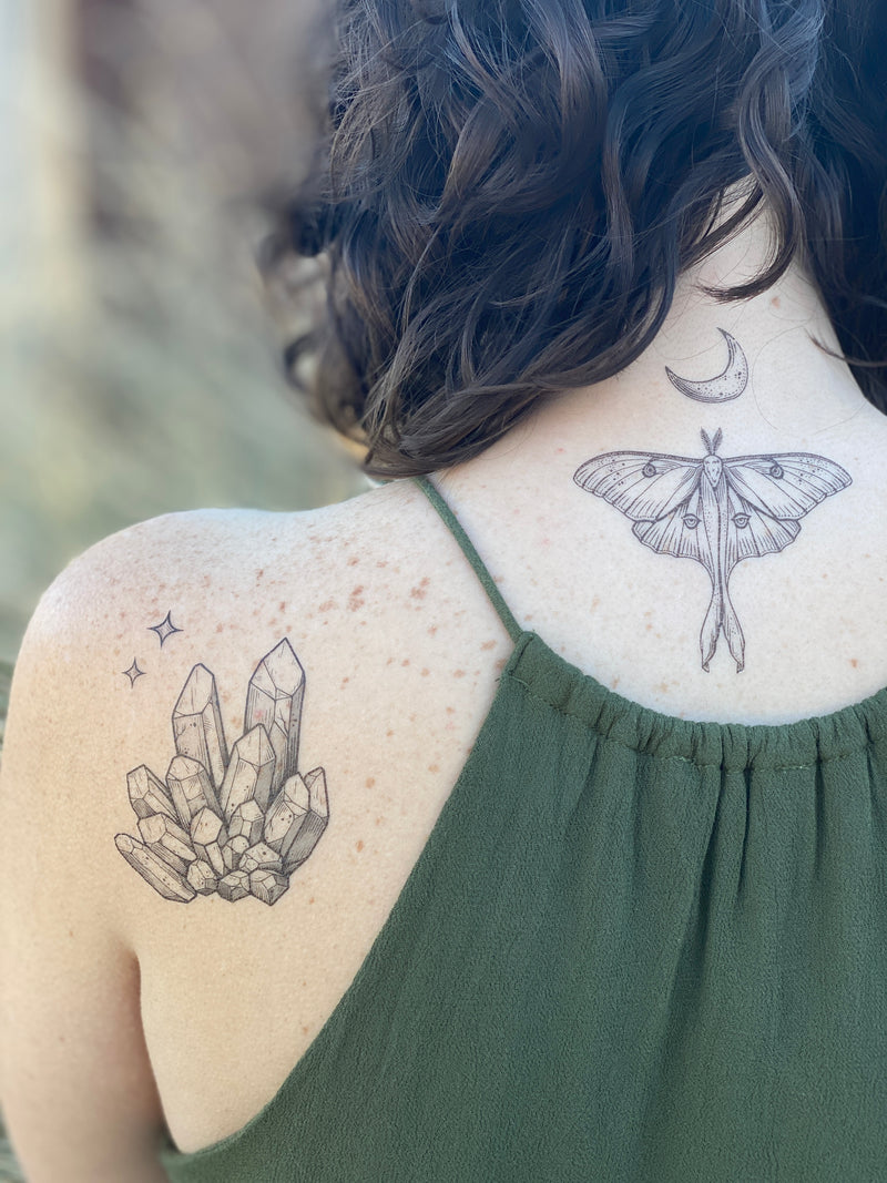 Luna Moth with crescent moon above it temporary tattoo on person neck wearing green in a blurred nature background 