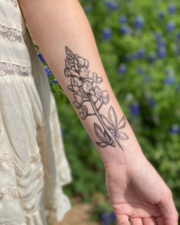 bluebonnet temporary tattoo on a persons arm with a blurred nature background 