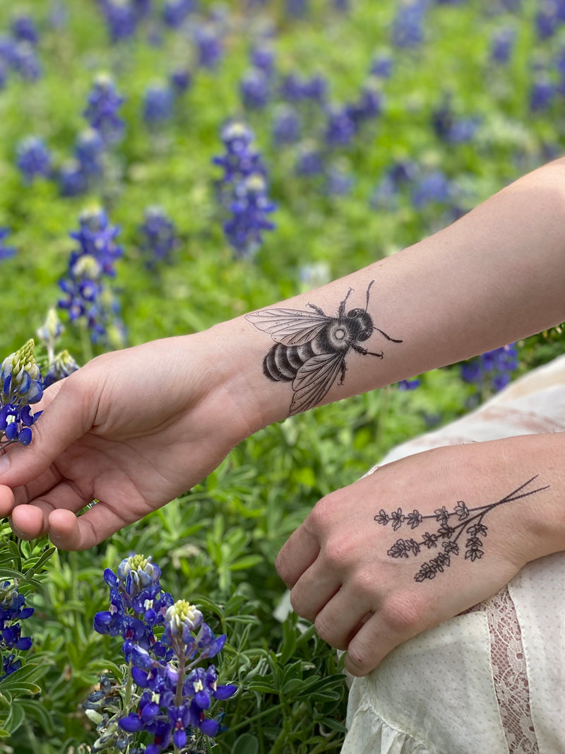 temporary tattoos on a person arm and hand in a field of flowers 