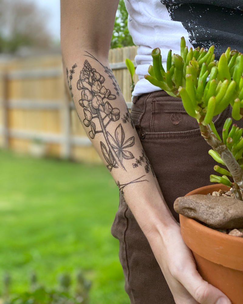 temporary tattoos on a persons arm with a brown and green blurred nature background 
