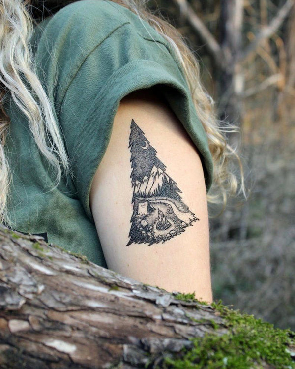Mountain camping temporary tattoo on persons upper arm wearing green in a brown nature background 