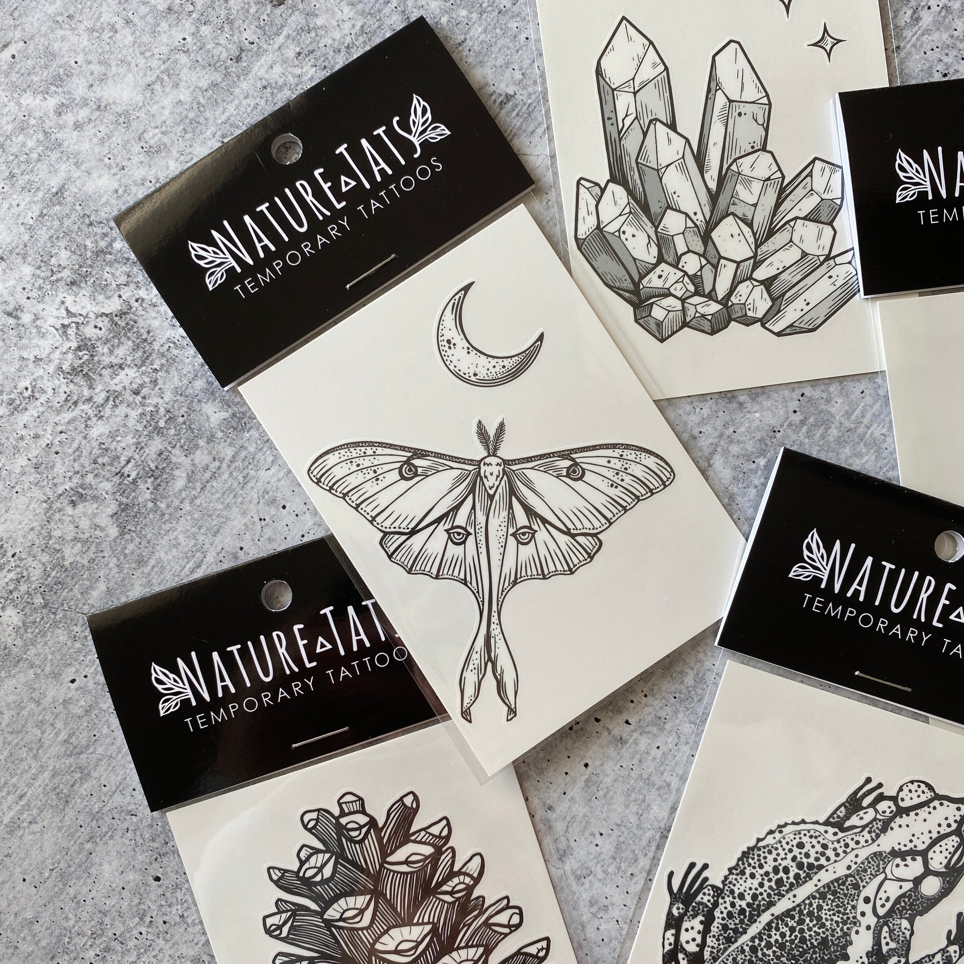 Luna moth with crescent moon above it temporary tattoo in packaging with a grey background 