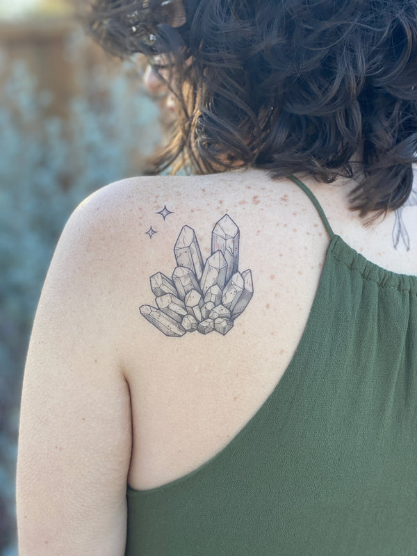 quartz crystal temporary tattoo on persons back wearing green in a blurred background 