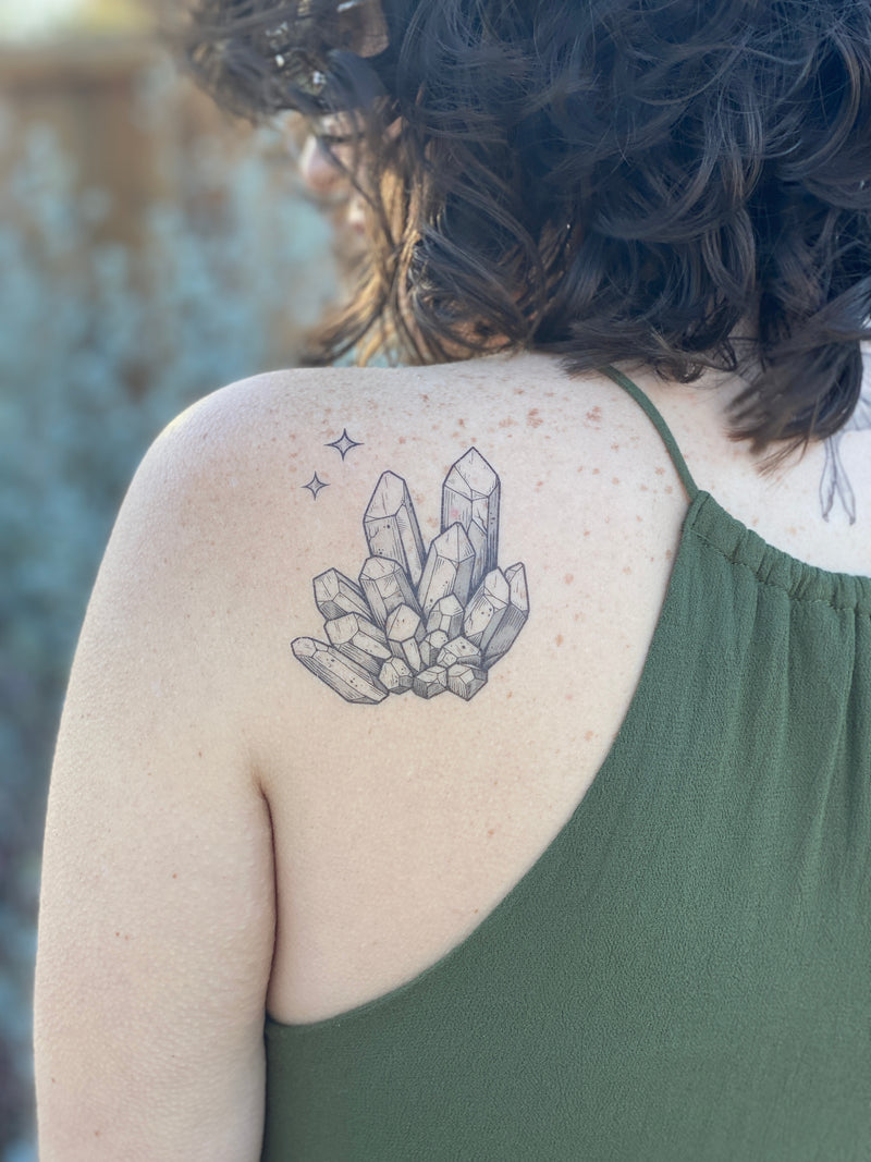 quartz crystal temporary tattoo on persons back wearing green in a blurred background 