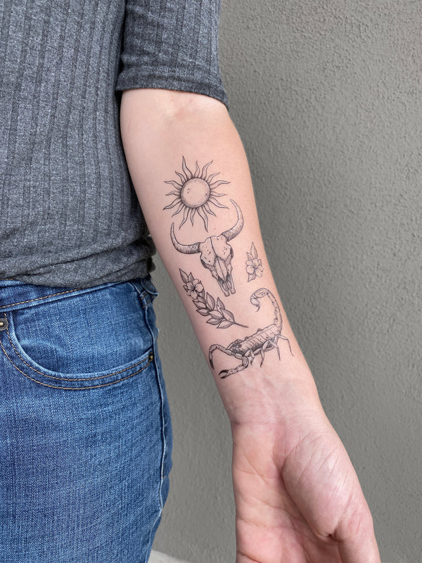 sunlit south temporary tattoo collection on persons arm wearing grey and blue with a grey background 